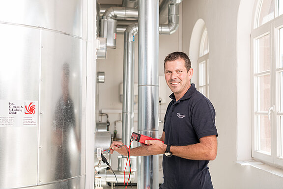 Mitarbeiter mit Messwerkzeugen an Heizungsanlage