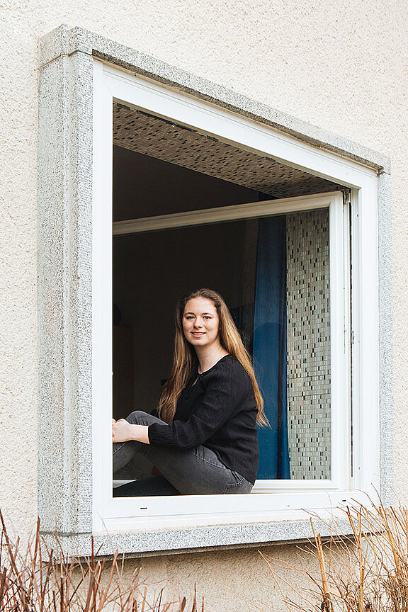 Lena Taschareck im Fensterrahmen sitzend