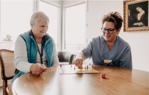 Ältere Dame spielt mit Pflegerin ein Gesellschaftsspiel