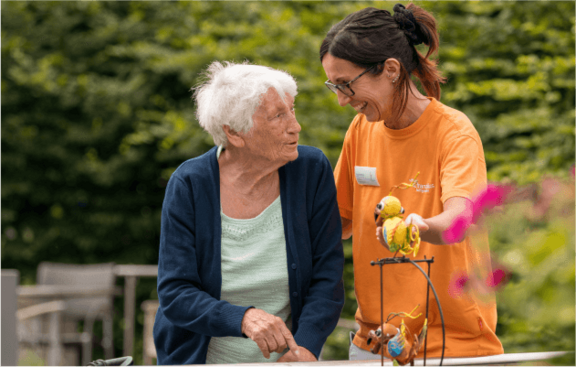 Pflegerin und Betreute spazieren im Garten