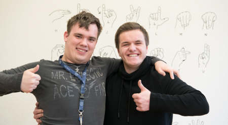 zwei junge Männer halten die Daumen hoch und lachen in die Kamera