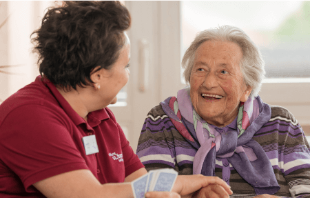 Pflegerin mit älterer Dame lachend